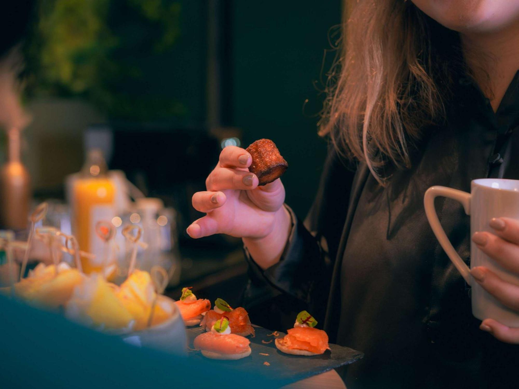 Nest Hotel Paris La Defense - Mgallery Collection Puteaux Exteriér fotografie A woman holding a piece of sushi